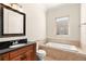 Bright bathroom with a soaking tub, window and single vanity sink with dark wood cabinets at 2660 Mirabella St, Henderson, NV 89052