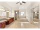 A full primary bathroom featuring a soaking tub, walk-in shower, dual sink vanity, and travertine tile flooring at 2660 Mirabella St, Henderson, NV 89052
