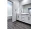Bathroom featuring double vanity with modern fixtures, white cabinets, and gray wood-look floors at 290 Mount Williamson St, Henderson, NV 89015