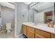 Well-lit bathroom with a single sink vanity, toilet, light gray walls, and wood-look floors at 317 Shimmering Moon St, Henderson, NV 89015