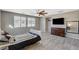 Bright bedroom featuring a ceiling fan and dresser with large TV, wood-look floors, and natural light at 317 Shimmering Moon St, Henderson, NV 89015