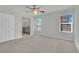 A bright bedroom with neutral carpet, ceiling fan, and two windows, offering comfort and style at 389 Scarlet Pine Ct, Henderson, NV 89044