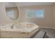 A luxurious bathroom featuring a jacuzzi tub with marble-like countertops and a large round mirror at 401 Altamira Rd, Las Vegas, NV 89145