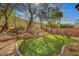 Backyard with green grass, decorative plants, brick edging, a retaining wall, trees, and pathway lights at 4593 Weitzman Pl, Las Vegas, NV 89141