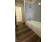 Bathroom featuring a tub with tiled walls and wood-look flooring at 567 Roxella Ln # D, Las Vegas, NV 89110