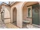 Covered entryway featuring arched openings, neutral stucco, stone pavers, a bench, and a wreath on the front door at 6904 Baylor Creek St, North Las Vegas, NV 89086
