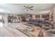 Spacious open-plan living room with wood floors, ceiling fan, dining table and large comfortable leather sofa at 6904 Baylor Creek St, North Las Vegas, NV 89086