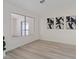 Bright living room with large window, modern artwork, and light wood-look flooring at 7138 Sixshooter Dr, Las Vegas, NV 89119