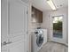 Modern laundry room boasts efficient washer and dryer set, storage, and direct access to the outside at 8116 Haywood Estate Ave, Las Vegas, NV 89113