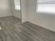 Bedroom with gray wood floors, a mirrored closet, and a window with blinds for natural light at 8244 Sickle Ln, Las Vegas, NV 89128