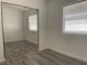 Bedroom with gray wood floors, a mirrored closet, and a window with blinds for natural light at 8244 Sickle Ln, Las Vegas, NV 89128