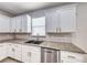 Bright kitchen featuring stainless steel dishwasher, granite countertops and white cabinets with gold hardware at 9629 Grouse Grove Ave, Las Vegas, NV 89148