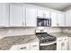 Well-lit kitchen showcases stainless steel oven, granite countertops, white cabinets and tiled backsplash at 9629 Grouse Grove Ave, Las Vegas, NV 89148