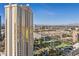 Exterior view of a modern condo tower with gold windows near a green space and cityscape at 135 E Harmon Ave # 221, Las Vegas, NV 89109