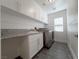 Well-lit laundry room with gray tile flooring, granite counters, and white cabinets above a modern washer and dryer at 150 Short Ruff Way, Las Vegas, NV 89148