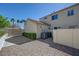 The backyard has gravel cover, a hedge, and a two-story home above at 1598 Bermuda Dunes Dr, Boulder City, NV 89005