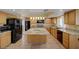 Open kitchen with stone counters, island, wood cabinets, and black appliances at 1598 Bermuda Dunes Dr, Boulder City, NV 89005