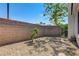 Simple backyard with gravel, a tree, and a brick wall providing privacy and a defined space at 2024 Riva Del Garda Pl, Las Vegas, NV 89134