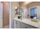 Neutral toned bathroom with a large mirror, single sink vanity with white cabinets, and a view of a bedroom beyond at 2024 Riva Del Garda Pl, Las Vegas, NV 89134