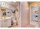 Neutral-toned bathroom with flowered wallpaper, mirror, sink and toilet adjacent to a hallway and washer dryer area at 2024 Riva Del Garda Pl, Las Vegas, NV 89134