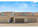 A row of townhomes featuring private garages and well-maintained landscaping under a clear blue sky at 2409 Bellinzona Pl, Henderson, NV 89044