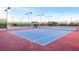 Outdoor tennis courts with blue and red surface areas enclosed with black fencing and overhead lighting at 2444 Gamma Ray Pl, Henderson, NV 89044