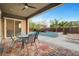 Covered patio with dining table and a view of the pool and the backyard with lush trees at 2583 Hazelburn Ave, Henderson, NV 89044
