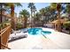 Community pool area featuring a unique shape, mature trees, and outdoor lounge furniture at 2611 S Durango Dr # 102, Las Vegas, NV 89117