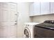 Convenient laundry room features modern washer, dryer, and ample overhead cabinet storage at 5525 Criollo Dr, Las Vegas, NV 89122