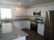 Well-lit kitchen featuring stainless steel appliances, white cabinets, and granite countertops at 5642 Sunset Amber Ave, Las Vegas, NV 89122