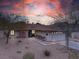 Charming single-story home with xeriscaping, a two-car garage, and a welcoming entrance against a vivid sunset sky at 6858 Groveview Ln, Las Vegas, NV 89103