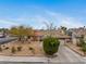 Inviting single-story home with mature trees, xeriscaping, a brick chimney, and a two-car garage at 6858 Groveview Ln, Las Vegas, NV 89103