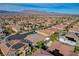 Aerial view of a residential area with terracotta rooftops, solar panels, and lush greenery against a mountain backdrop at 9359 Brownstone Ledge Ave, Las Vegas, NV 89149