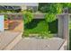 Birds eye view of fenced-in backyard features a well-maintained lawn, lush trees, a small patio, and decorative rock at 9359 Brownstone Ledge Ave, Las Vegas, NV 89149