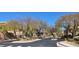 A residential street view with tree lined entrance and gate at 10091 Sand Key St, Las Vegas, NV 89178