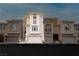 Exterior of three-story townhomes with varied neutral-tone paint, garage and balcony, offering curb appeal at 10091 Sand Key St, Las Vegas, NV 89178