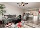 Comfortable living room with a gray sofa, recliner, ceiling fan, and stylish rug, open to the kitchen at 10091 Sand Key St, Las Vegas, NV 89178
