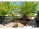 View of the landscaped common area featuring mature trees, a wrought iron fence, and a paved walkway at 10809 Garden Mist Dr # 2072, Las Vegas, NV 89135
