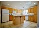 Well-lit kitchen with wood cabinets, tile floors, granite countertops, and a kitchen island at 1241 Gingerbread Man Ave, Las Vegas, NV 89183