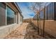 Narrow side yard with desert landscaping, framed by a brick wall and young trees, offering privacy at 127 Crimson Cactus Ave, Henderson, NV 89011