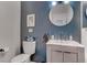 Stylish bathroom with a modern vanity, round mirror, and blue accent wall at 1847 Avacado Ct, Henderson, NV 89014