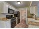 Bright kitchen features white cabinets, black appliances, tile counters and flooring, and adjacent pantry at 2120 Ramrod Ave # 415, Henderson, NV 89014