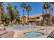 Community pool with lounge chairs, tables and chairs and tall palm trees at 2120 Ramrod Ave # 415, Henderson, NV 89014