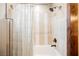 Close up of tiled bathtub/shower combo with neutral colored shower curtain and black fixtures at 479 Apogee, Mesquite, NV 89027