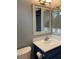 Well-lit bathroom with a framed mirror above a blue vanity and white countertop, offering a clean aesthetic at 7728 Barbican Ct, Las Vegas, NV 89147