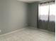Neutral-toned bedroom showcasing a window with curtains and tile flooring at 7728 Barbican Ct, Las Vegas, NV 89147