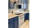 Functional kitchen features blue cabinets, laminate countertops and white appliances at 7728 Barbican Ct, Las Vegas, NV 89147