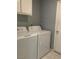 Functional laundry area equipped with a washer and dryer set, complemented by overhead cabinets at 7728 Barbican Ct, Las Vegas, NV 89147