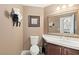 Cozy bathroom with a toilet, sink, and vanity with unique wall decorations and a large framed mirror at 9517 Spanish Steps Ln, Las Vegas, NV 89117