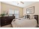 Comfortable bedroom with a ceiling fan, large window, and dresser with ample storage space at 9517 Spanish Steps Ln, Las Vegas, NV 89117